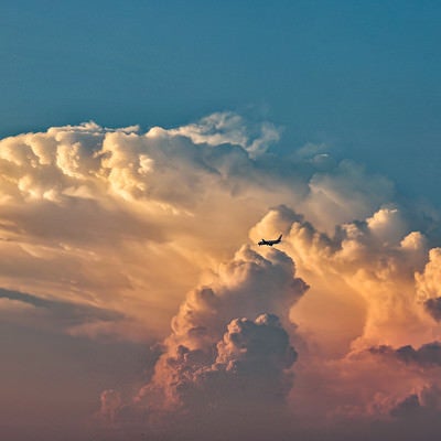 夕焼けに染まる入道雲と飛行機の写真