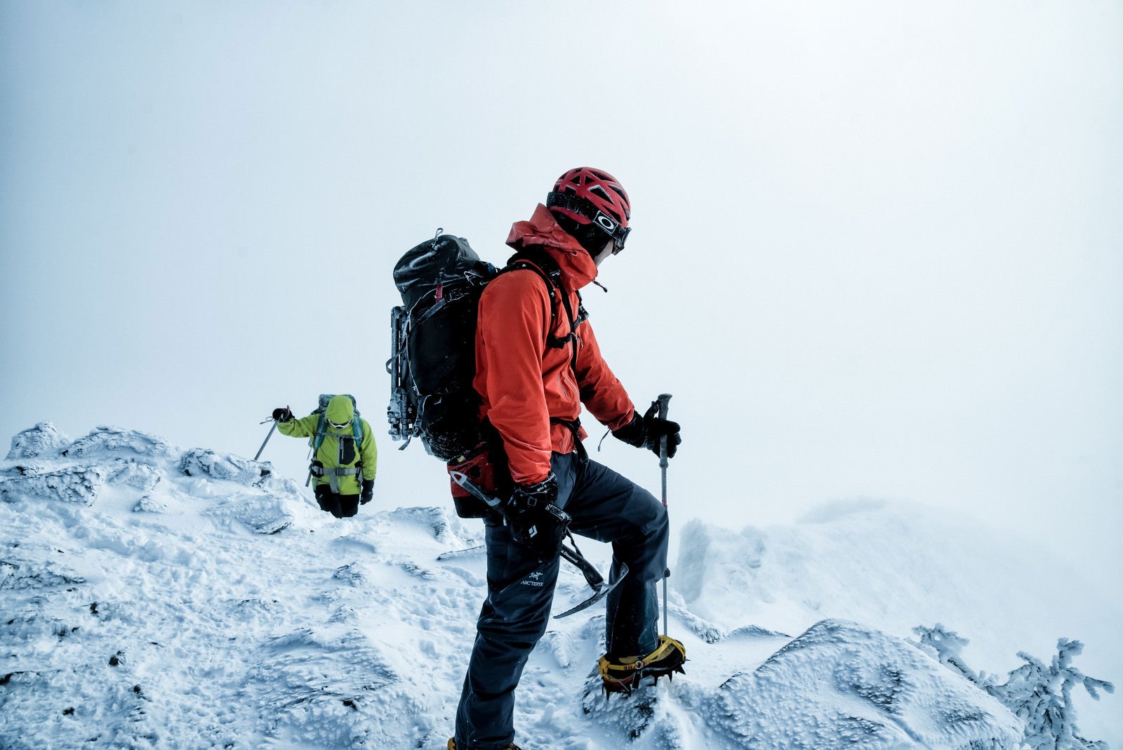 「雪山で下山路を見つめる登山者の男性」の写真