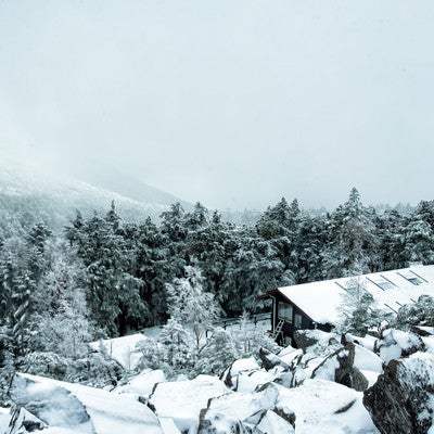 視界不良の雪山と雪に覆われた高見石小屋の写真