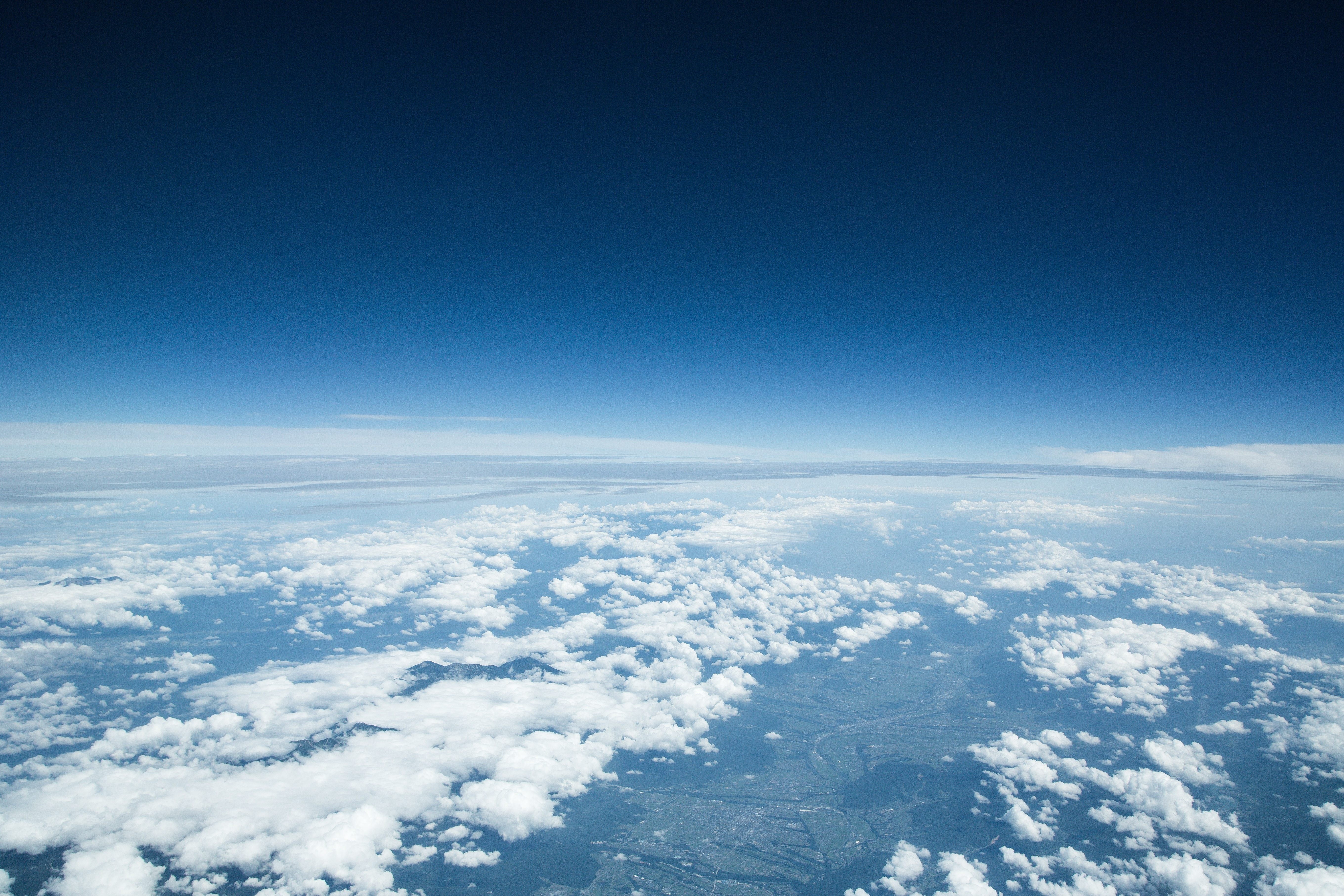 雲海を抜けた濃い青空と地球の曲線が見える高高度からの眺望の無料の