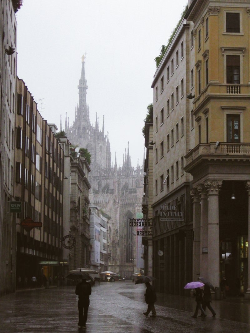 「ミラノの大聖堂へと続く路地で傘を差す通行人（イタリア）」の写真