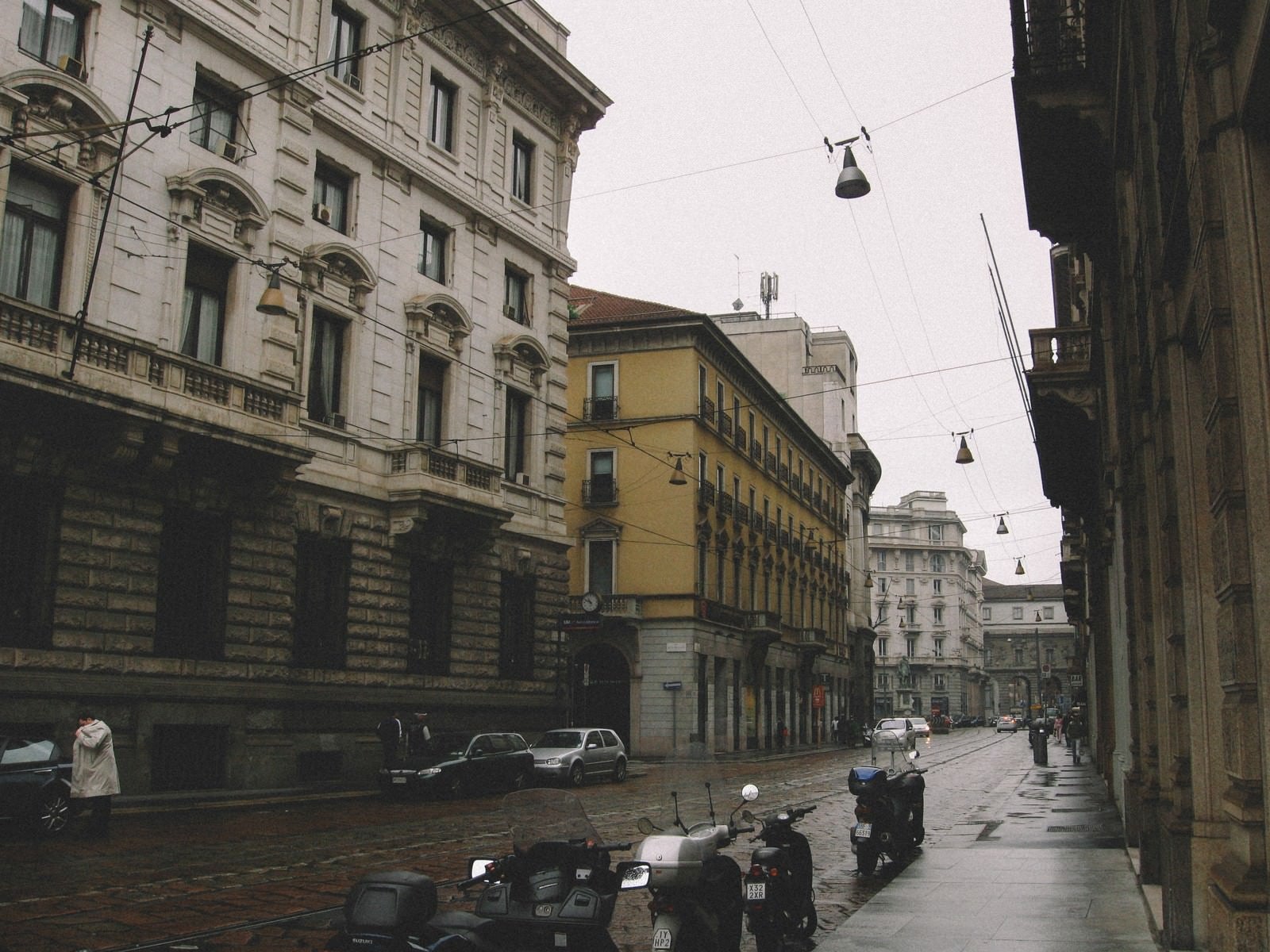 「雨上がりの濡れた路地に停められたバイク（イタリア ミラノ）」の写真