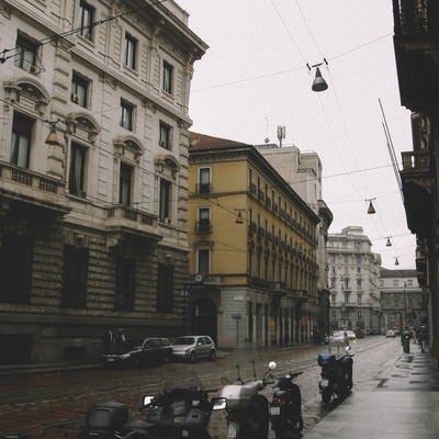 雨上がりの濡れた路地に停められたバイク（イタリア ミラノ）の写真