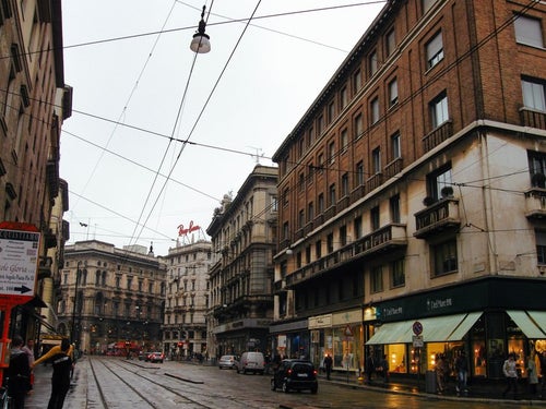 街角にあるレンガ造りの建物とミラノの街並み（イタリア）の写真