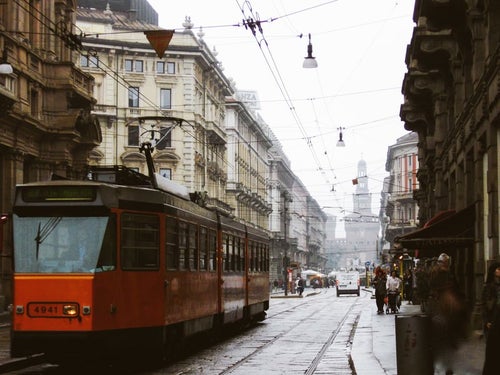 ミラノの時計台へと続く路地を走る路面電車と街並み（イタリア）の写真