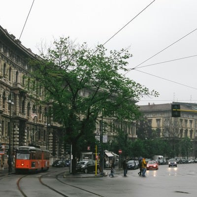 ミラノの街並みと車道と平行して走る路面電車（イタリア）の写真