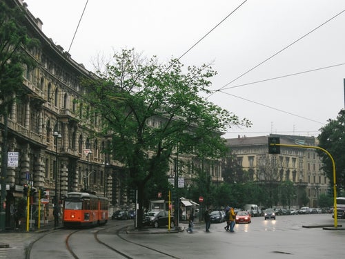 ミラノの街並みと車道と平行して走る路面電車（イタリア）の写真