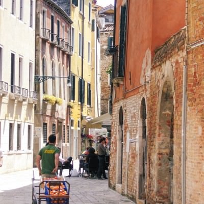 ベネチアの街並みと果物売りの青年（イタリア）の写真