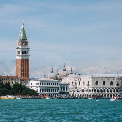 ヴェネツィアを流れる川の向こうにみえる大鐘楼とサン マルコ寺院の屋根（イタリア）の写真
