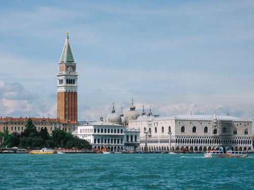 ヴェネツィアを流れる川の向こうにみえる大鐘楼とサン マルコ寺院の屋根（イタリア）の写真