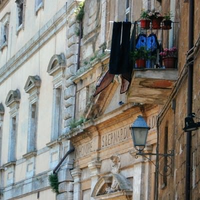 オルヴィエートの出窓に並ぶ花と洗濯物（イタリア）の写真
