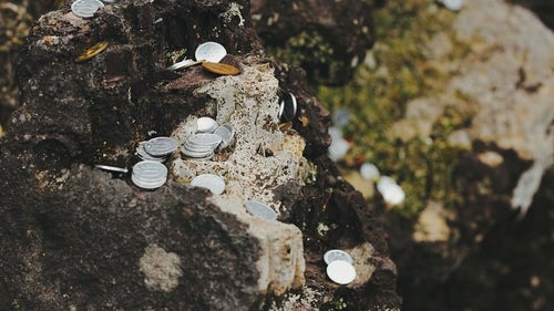 岩場に置かれた小銭の写真