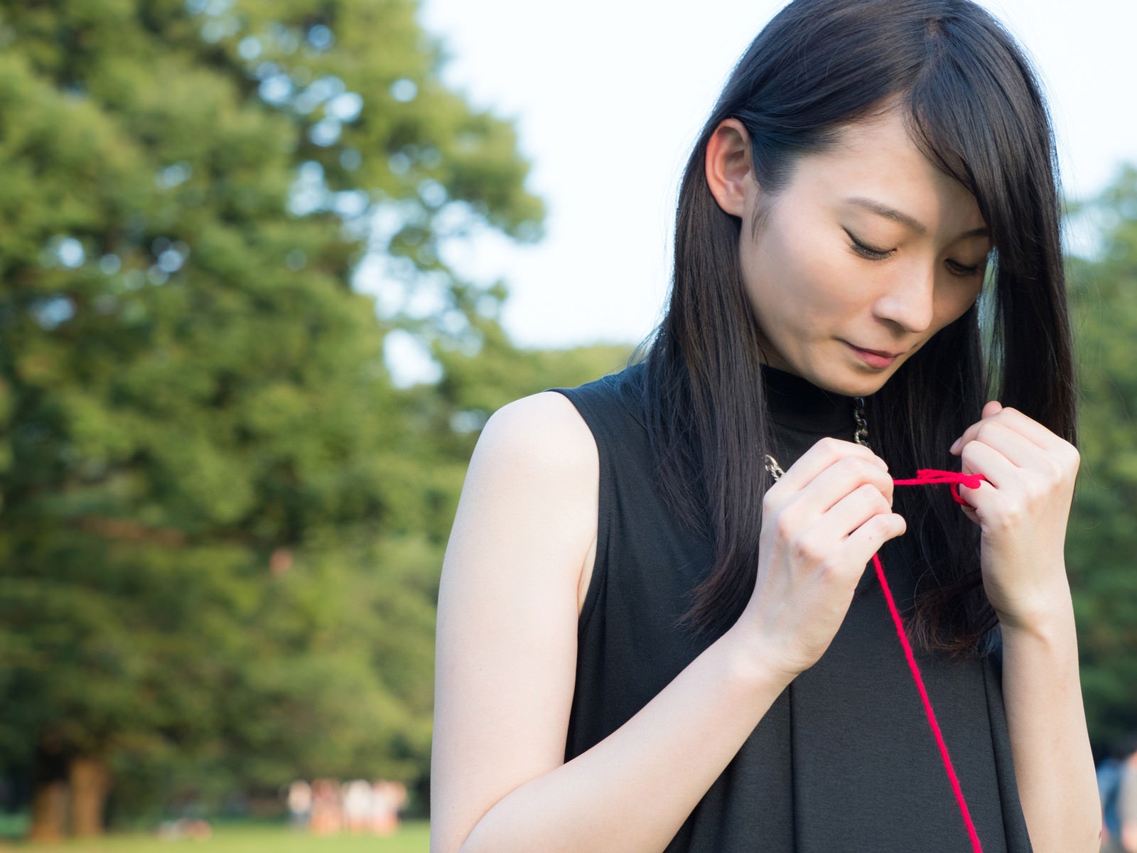 「ちぎれた赤い糸を結び直す女性」の写真［モデル：たけべともこ］