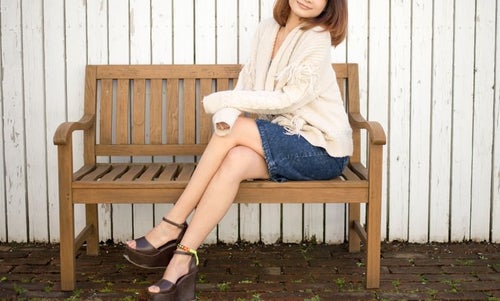 ベンチに腰掛ける若い女性の写真