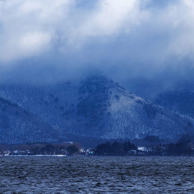 雪化粧した山と猪苗代湖の写真