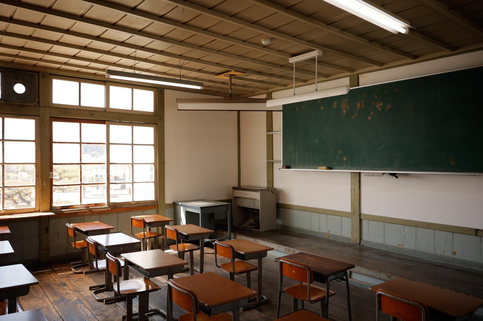 「学びの窓から降り注ぐ光と黒板と学習机」の写真