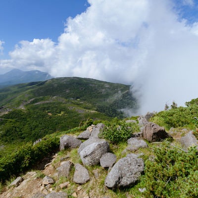 岩が残る登山道と雲がかかる天狗ノ奥庭（天狗岳）の写真