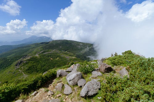 岩が残る登山道と雲がかかる天狗ノ奥庭（天狗岳）の写真