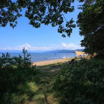 浜辺での海水浴と広がる猪苗代湖の写真