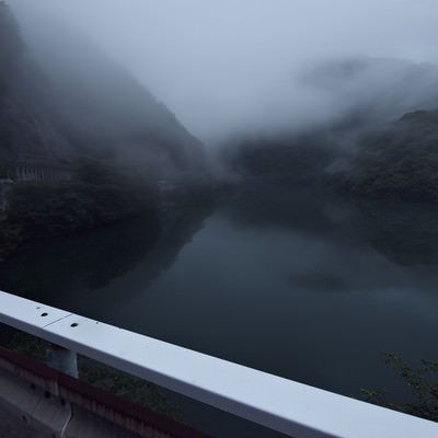 霧に覆われる山と湖面（富山県南砺市）の写真