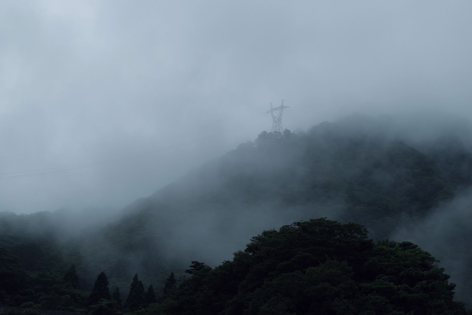 「山を覆う濃霧と鉄塔（富山県南砺市）」の写真