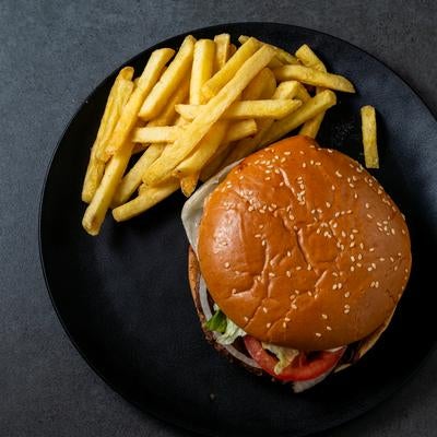 黒い皿に盛られたゴマ付きハンバーガーとフライドポテトの写真