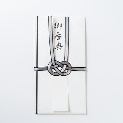 御香典と表書きされた黒白の水引で結ばれた白い不祝儀袋の写真