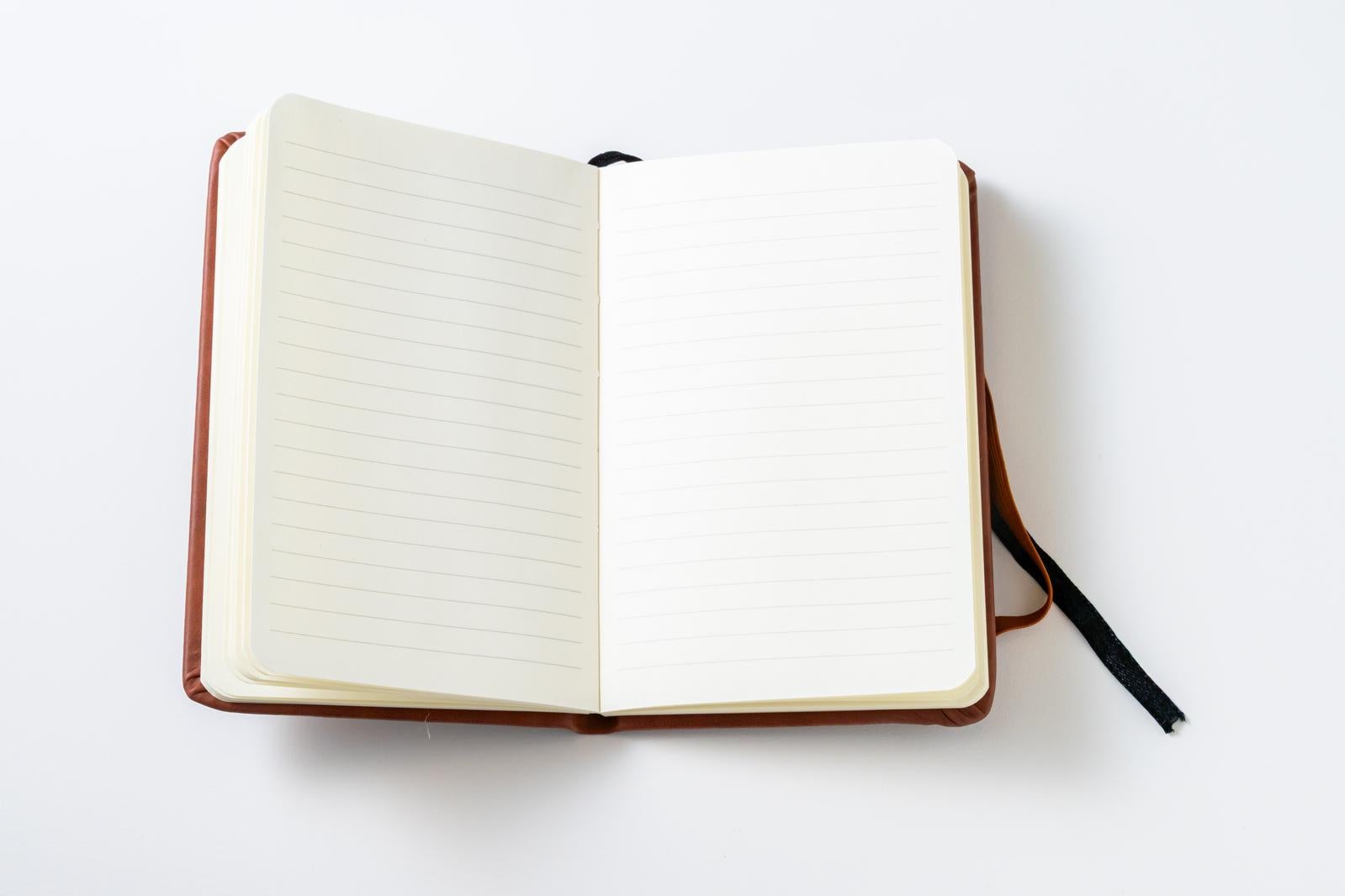 茶色の革表紙で見開きになった手帳、左に横罫線、右に白紙ページ