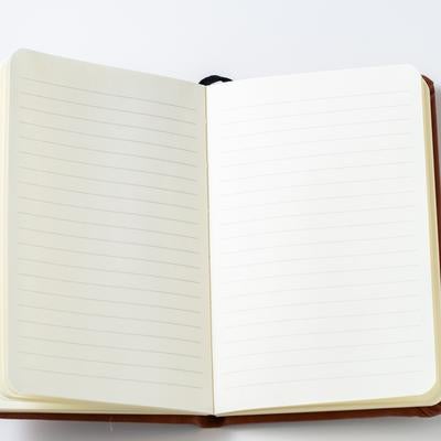 茶色のレザーカバーで開かれた罫線入り手帳の写真