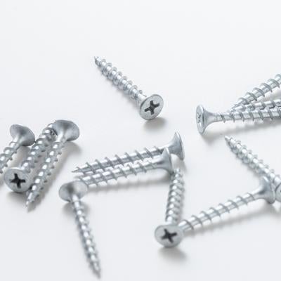 白い背景に無造作に配置された銀色のネジとビスの工具類の写真