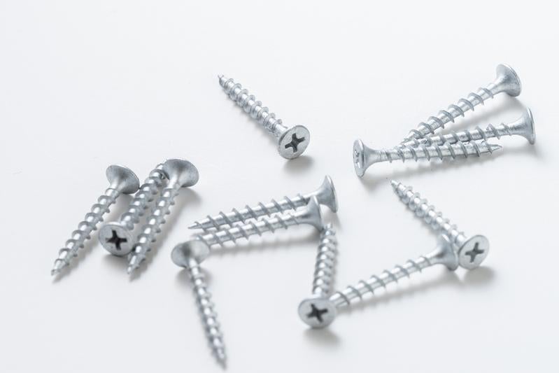 白い背景に無造作に配置された銀色のネジとビスの工具類の写真
