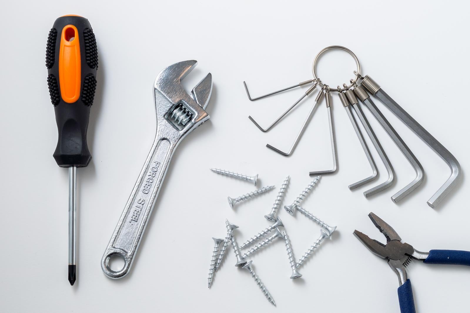 白い背景に並べられたドライバー、モンキーレンチ、六角レンチ、ペンチ、ビスなどの工具セット