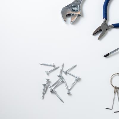 白い背景に配置された作業工具とネジ、六角レンチの写真