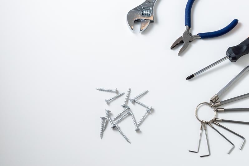 白い背景に配置された作業工具とネジ、六角レンチの写真