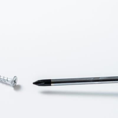 白い背景に置かれたプラスドライバーとネジの写真