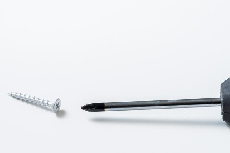 白い背景に置かれたプラスドライバーとネジの写真