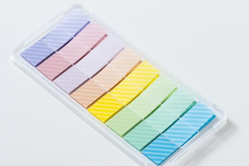 レインボーカラーの付箋が透明プラスチックケースに整理された状態の写真
