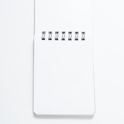 白背景に置かれたリング式メモ帳と文具ステーショナリーの写真