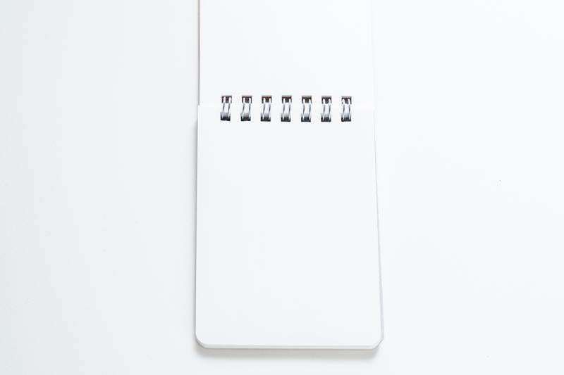 白背景に置かれたリング式メモ帳の写真