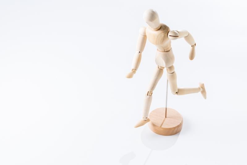 走るポーズの木製デッサン人形と木製台座の写真