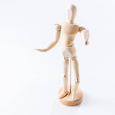 右手を前に伸ばし左手を腰に当てる木製デッサン人形の写真