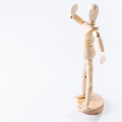 右腕を高く掲げる木製デッサン人形の写真