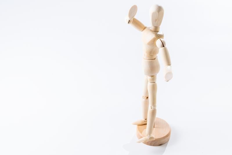 右腕を高く掲げる木製デッサン人形の写真