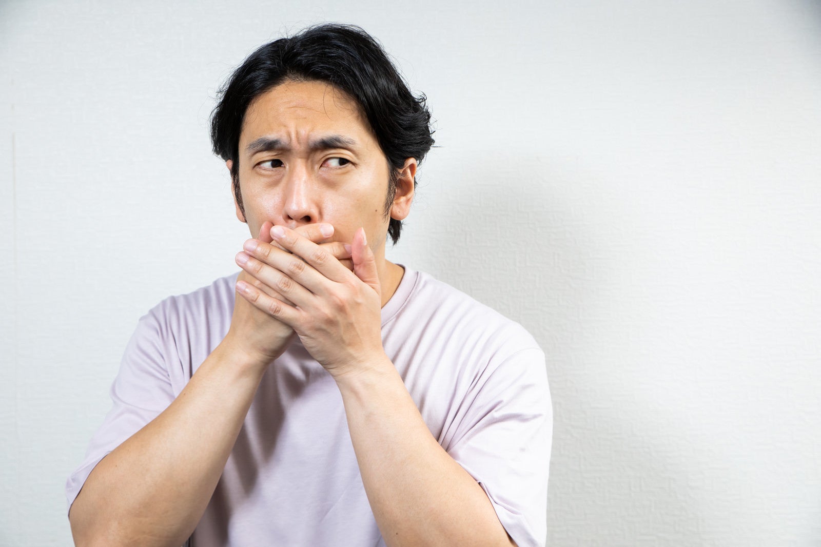 「口臭が漏れないように口を覆う男性」の写真［モデル：大川竜弥］