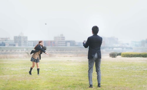 放課後に彼氏とキャッチボールする女子高生の写真