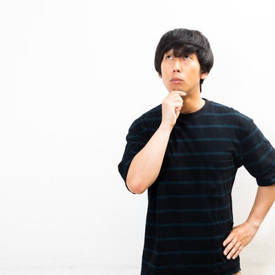 顎に手を当て不思議がる男性の写真