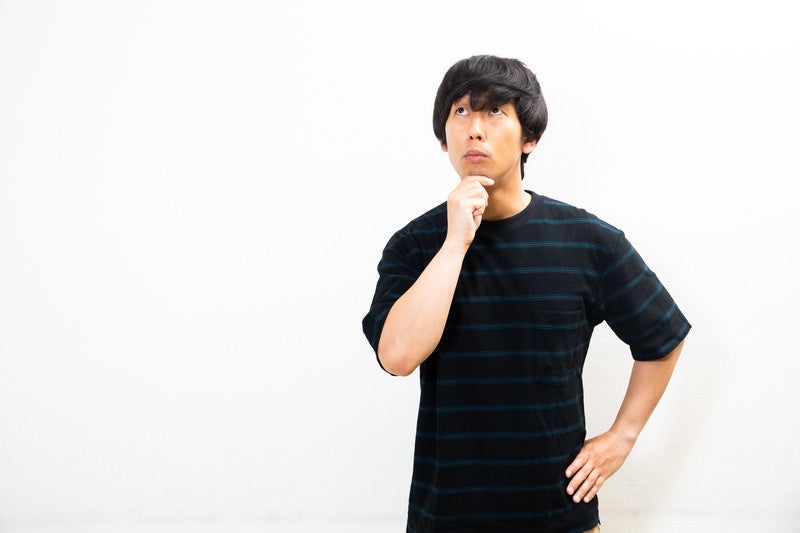 顎に手を当て不思議がる男性の写真