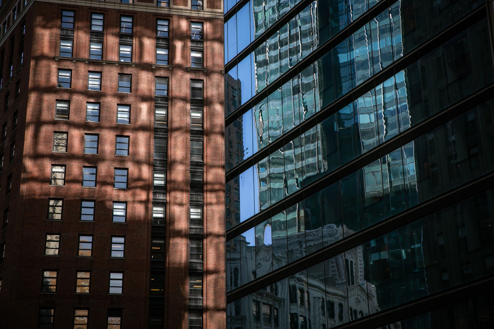 「ガラス張りの窓に映りこむニューヨークの建物」の写真