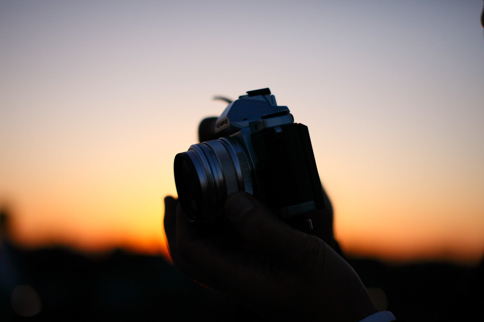 「夕焼けに生えるカメラシルエット」の写真