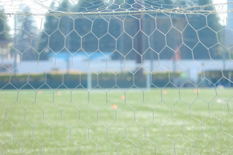サッカー試合前に静まり返るピッチサイド・ゴールネットの写真
